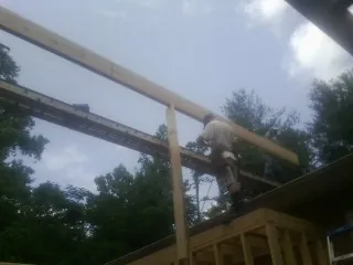Carpenter setting a ridge beam over a new addition frame — Ice Dam Removal by Roofing Brothers in Amberson