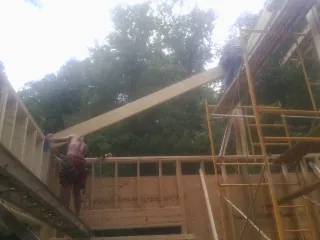Carpenter raising a rafter beam on a new second story frame in Amberson