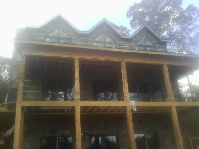 Dormers and porch framing on a large log home under construction — Roof Coating work by our crew in Amberson