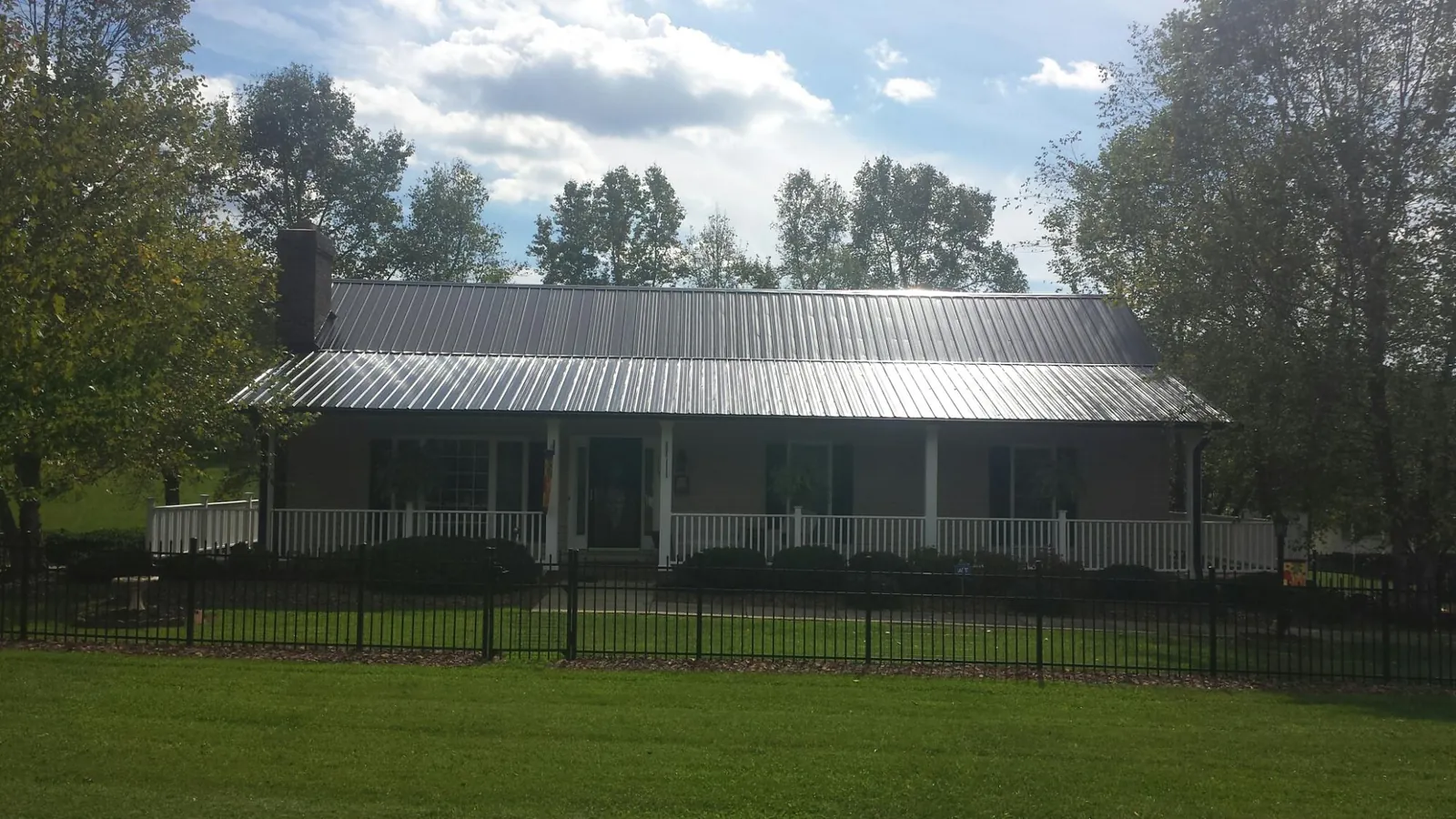Gray metal roof on a brick ranch with a full width front porch — Gutter Guard Installation work by our crew in Amberson