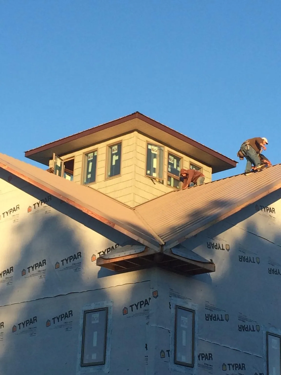 Roofers working around a rooftop cupola on a new metal roof at sunset — Roof Waterproofing in Amberson by Roofing Brothers